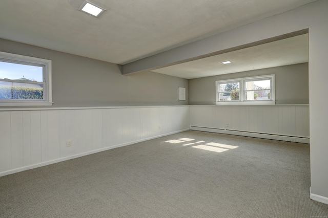 carpeted empty room with a baseboard heating unit and a wainscoted wall