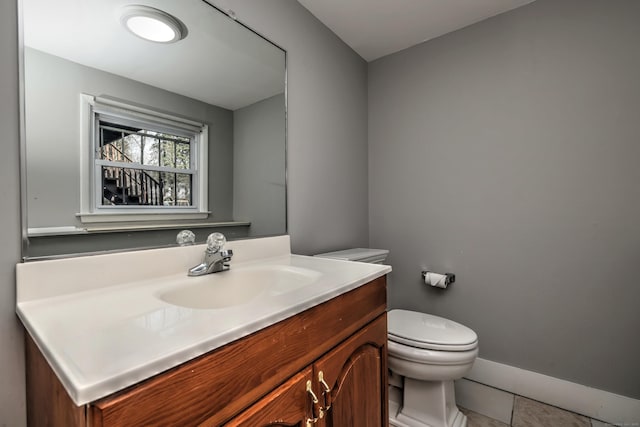 bathroom with toilet, tile patterned floors, vanity, and baseboards