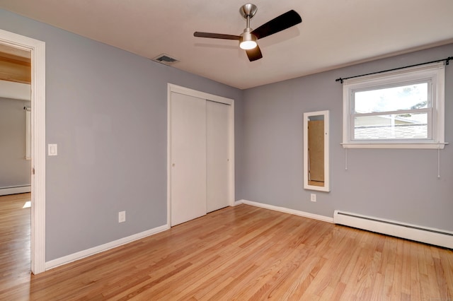 unfurnished bedroom with light wood-style flooring, a baseboard radiator, baseboard heating, baseboards, and visible vents