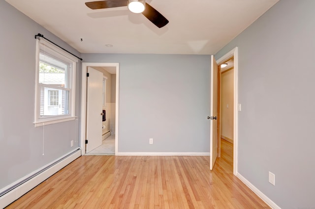 unfurnished room with ceiling fan, light wood-style flooring, a baseboard heating unit, and baseboards