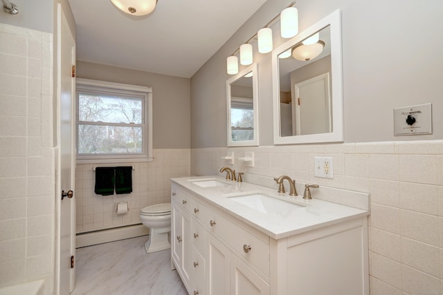 bathroom with baseboard heating, toilet, tile walls, and a sink