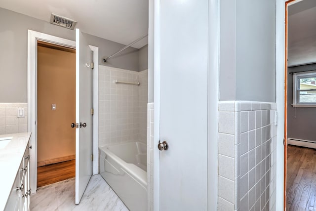 bathroom with visible vents, tile walls, shower / bathing tub combination, vanity, and wainscoting