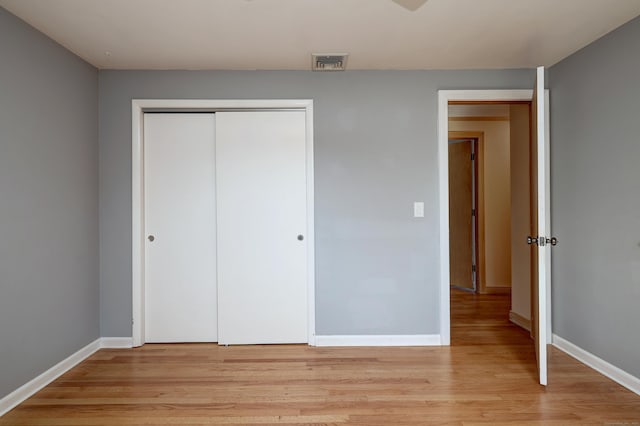 unfurnished bedroom featuring a closet, visible vents, baseboards, and light wood-type flooring