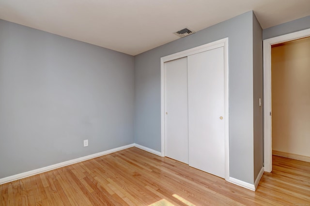 unfurnished bedroom with baseboards, visible vents, light wood-type flooring, and a closet