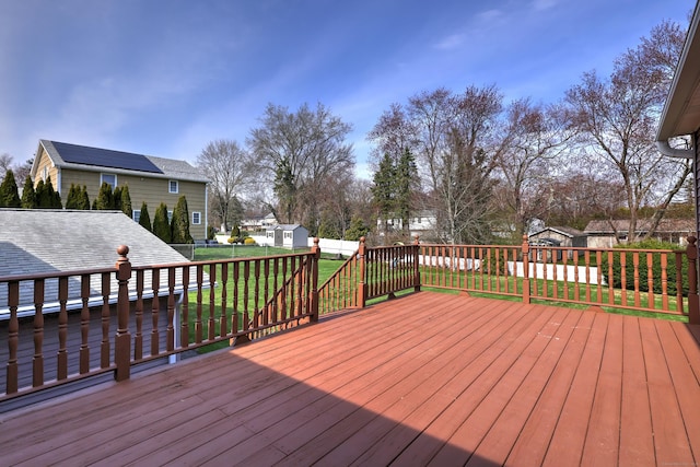 wooden deck featuring an outdoor structure, a storage shed, a yard, and a fenced backyard