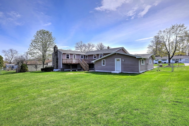 rear view of property featuring a chimney, fence, a deck, and a lawn
