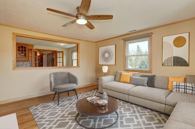 living area featuring ceiling fan, baseboards, wood finished floors, and plenty of natural light