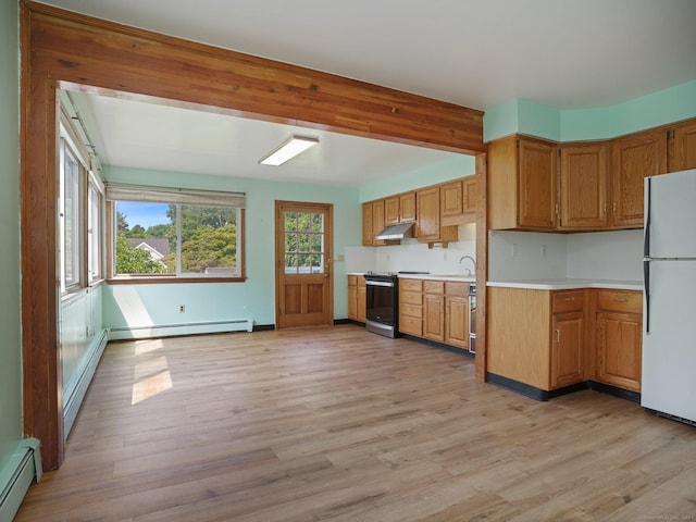 kitchen with a baseboard radiator, light countertops, under cabinet range hood, range with electric stovetop, and freestanding refrigerator