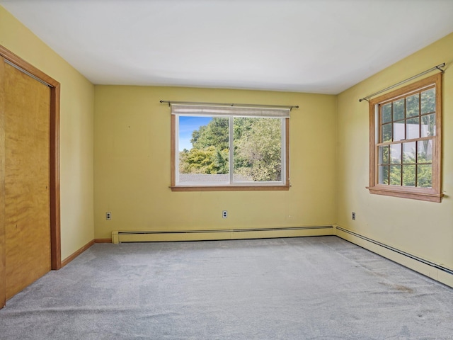 carpeted spare room with baseboards, baseboard heating, and a healthy amount of sunlight