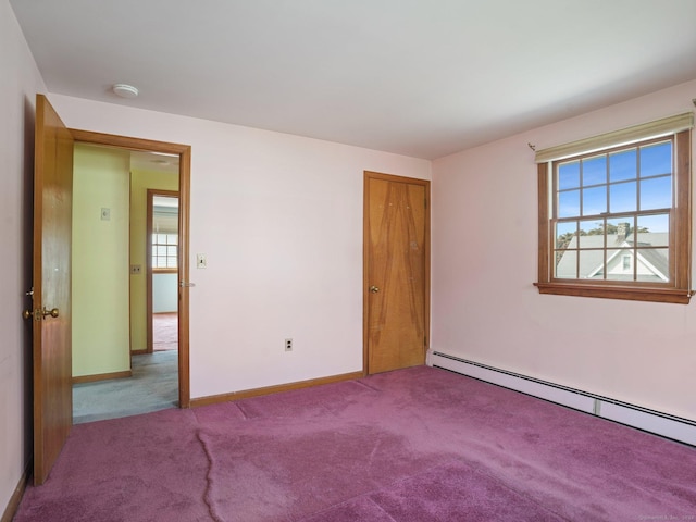 carpeted spare room featuring baseboards and a baseboard heating unit