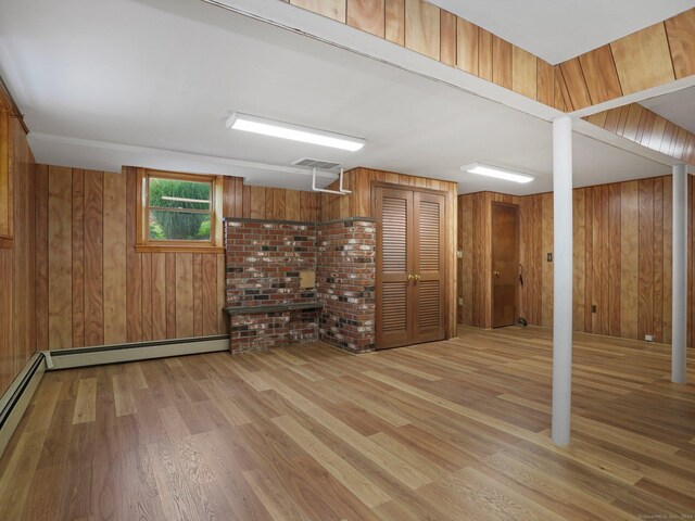 basement featuring visible vents, wood finished floors, a baseboard heating unit, and wooden walls