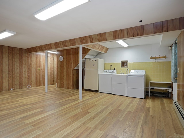clothes washing area with light wood-style floors, laundry area, separate washer and dryer, and a baseboard heating unit
