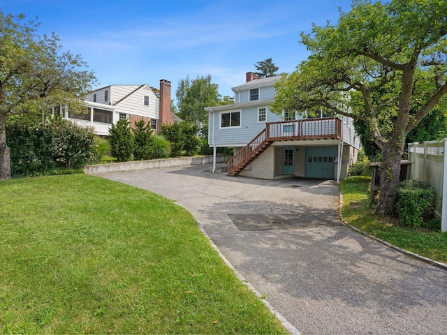 view of front of property with stairs, a chimney, an attached garage, aphalt driveway, and a front lawn