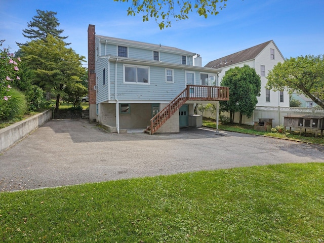 view of front of property featuring a wooden deck, driveway, stairs, and a chimney