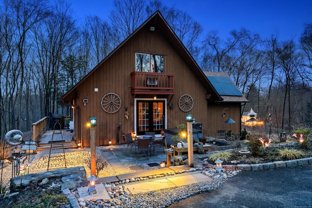 162 Hattertown Rd, Newtown, CT 06470 - rustic home featuring roof mounted solar panels, a wooden deck, a patio area, french doors, and roof with shingles
