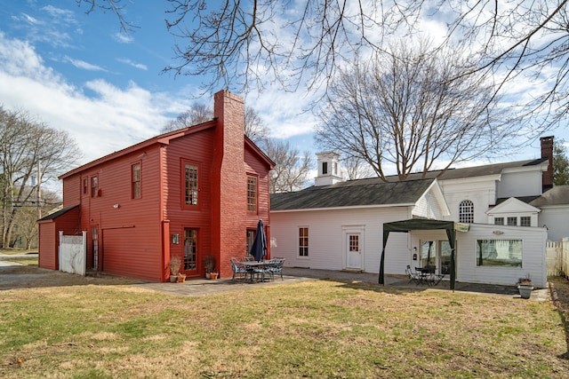 24-26 Lyme St, Old Lyme, CT 06371 - rear view of property featuring a chimney, a patio, and a yard