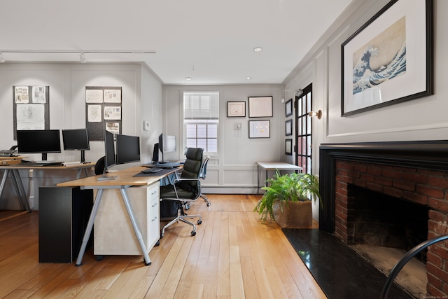 24-26 Lyme St, Old Lyme, CT 06371 - office space featuring a baseboard radiator, light wood-style flooring, a brick fireplace, and track lighting
