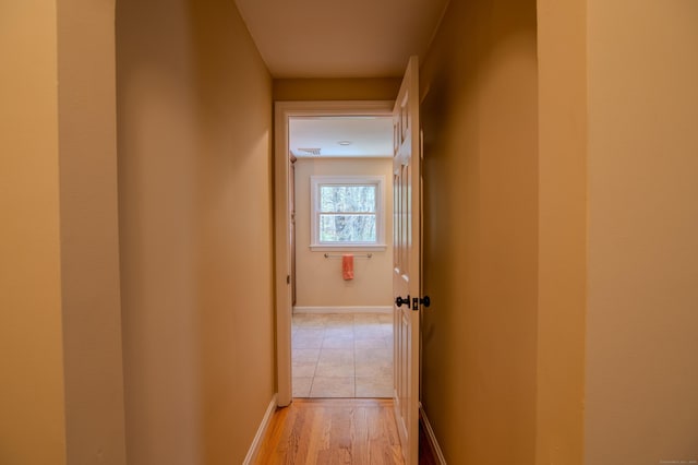 hall with light wood-style floors and baseboards
