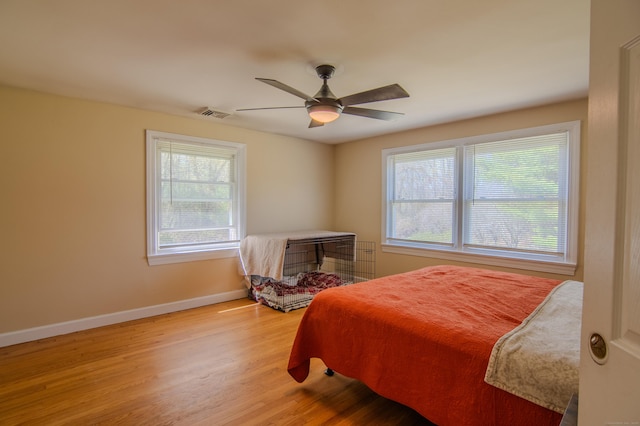 bedroom featuring baseboards, multiple windows, wood finished floors, and visible vents