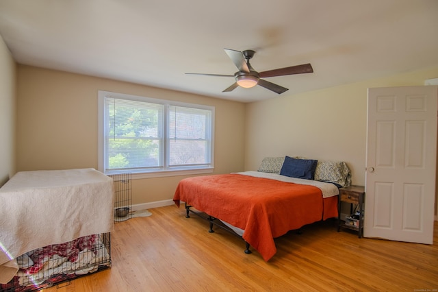 bedroom with a ceiling fan, baseboards, and light wood-style flooring