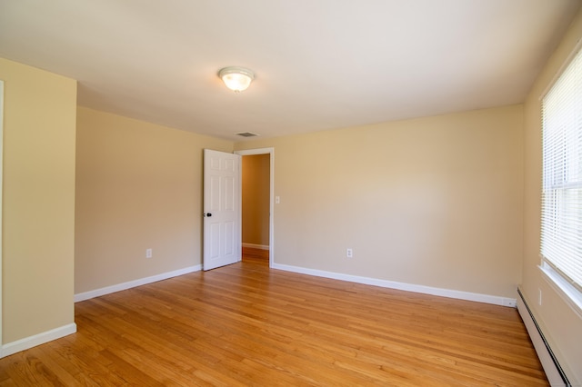 unfurnished room featuring baseboards, a baseboard radiator, light wood-style flooring, and visible vents