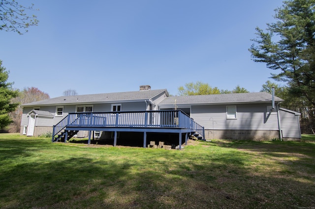 back of property featuring a lawn, a wooden deck, a chimney, and stairway
