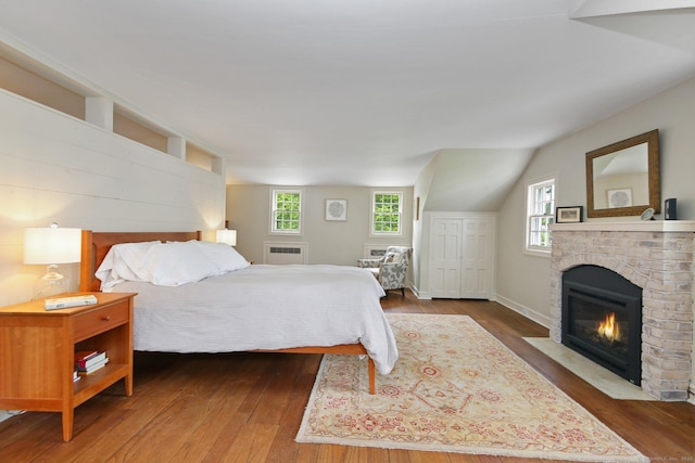 167 Skunk Ln, Wilton, CT 06897 - bedroom featuring hardwood / wood-style flooring, multiple windows, a brick fireplace, radiator, and vaulted ceiling