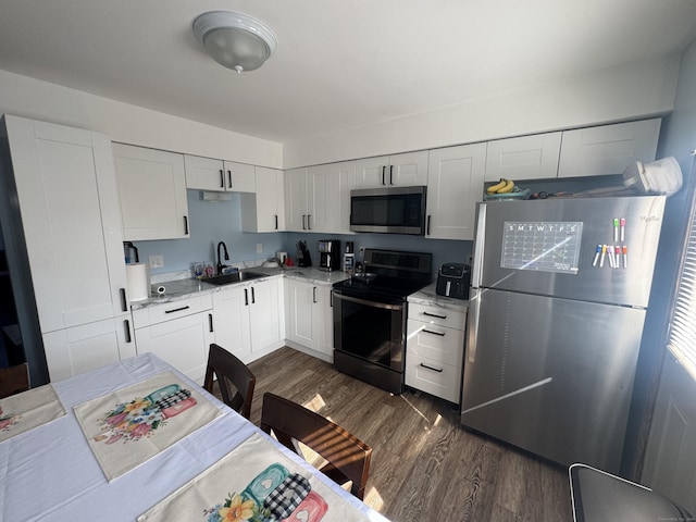kitchen with white cabinets, a sink, stainless steel appliances, and dark wood-style floors