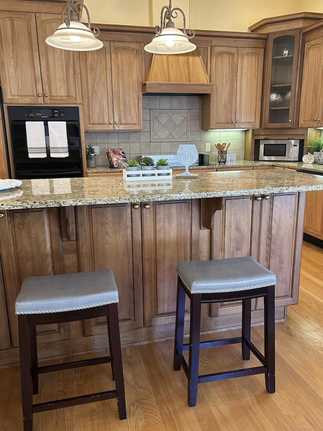 21 Autumn Cir, Rocky Hill, CT 06067 - kitchen featuring black oven, stainless steel microwave, light wood-style flooring, and tasteful backsplash