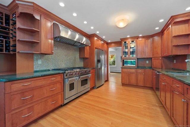kitchen featuring open shelves, stainless steel appliances, wall chimney range hood, light wood-type flooring, and decorative backsplash