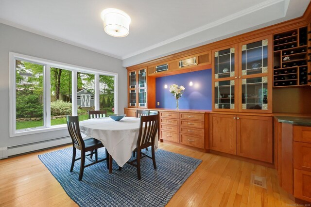 dining space with baseboard heating, light wood-style floors, and ornamental molding