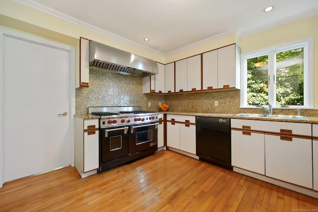 kitchen with range with two ovens, wall chimney range hood, dishwasher, a sink, and light wood-style flooring
