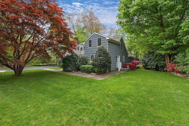 view of side of property with a yard and a chimney