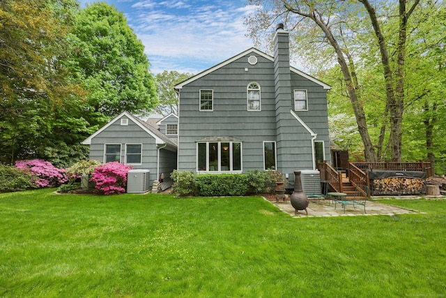 rear view of property with a patio, a chimney, central AC unit, and a lawn