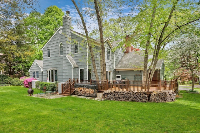 back of property with a chimney, a deck, a yard, and a patio