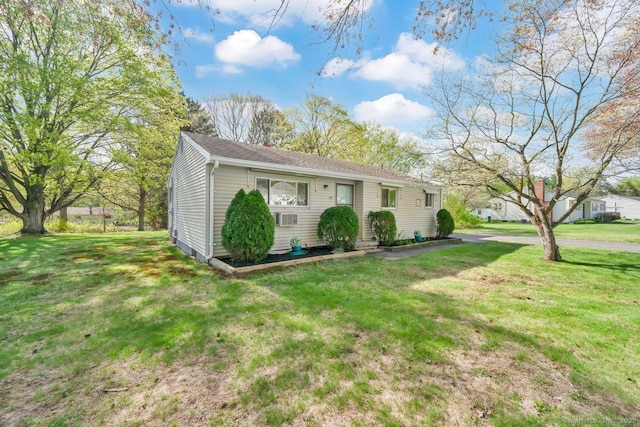 ranch-style house featuring a shingled roof and a front yard