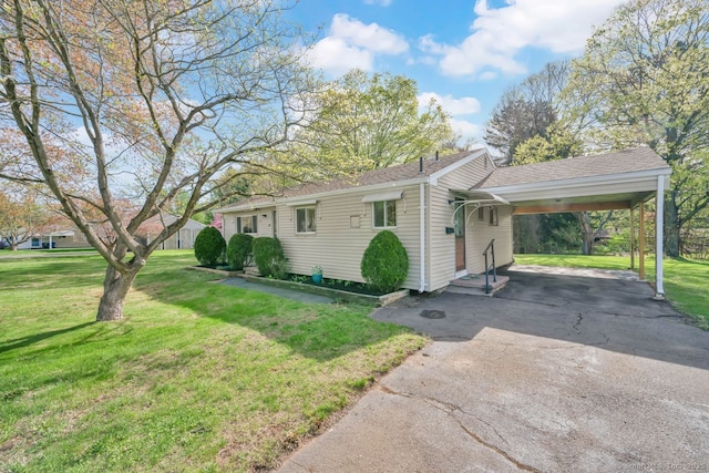 view of front of home featuring an attached carport, driveway, a shingled roof, and a front lawn