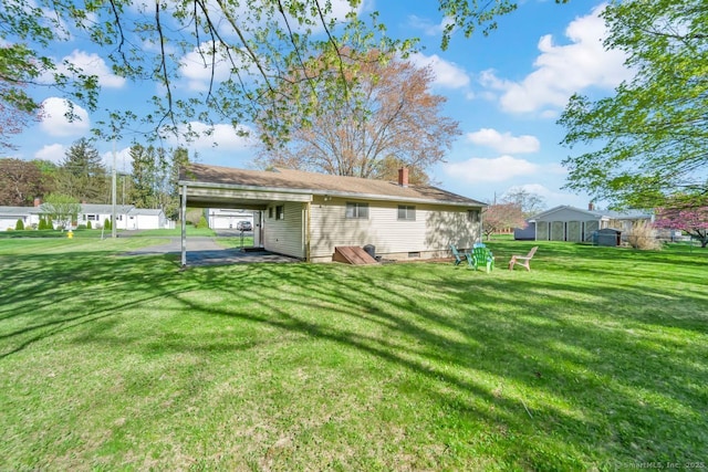 rear view of property with a lawn, a chimney, and a carport