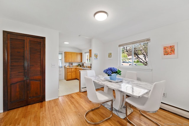 dining room with baseboards, a baseboard heating unit, and light wood-type flooring