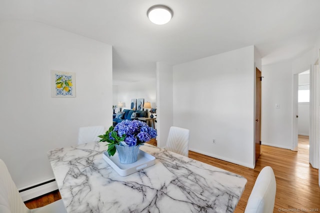 dining room featuring baseboards, wood finished floors, and baseboard heating