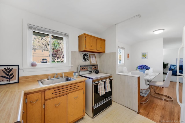 kitchen featuring a sink, electric range oven, light countertops, plenty of natural light, and lofted ceiling