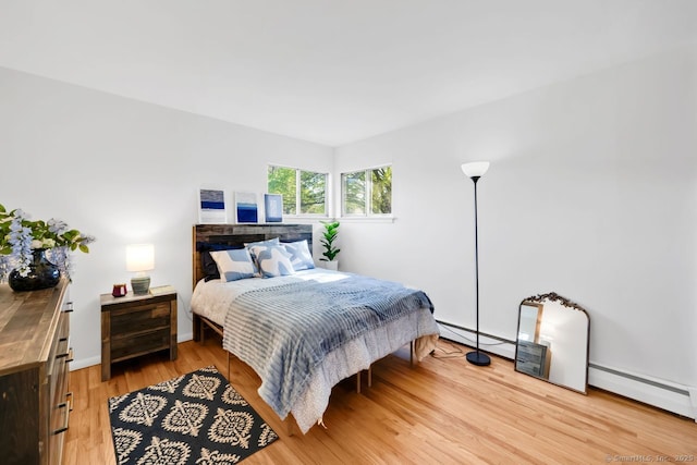 bedroom with baseboards, a baseboard heating unit, a baseboard radiator, and light wood-style floors