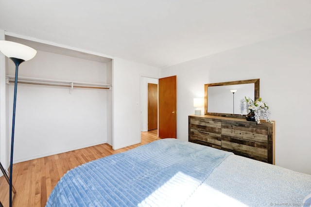 bedroom with baseboards, wood finished floors, and a closet