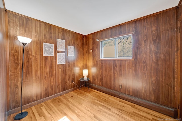 empty room with wooden walls, baseboards, and wood finished floors