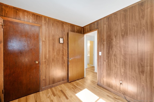 unfurnished bedroom featuring baseboards, wood walls, and wood finished floors