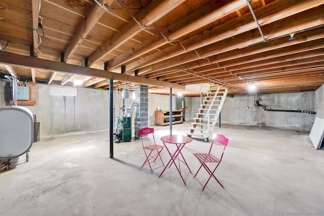 unfinished basement with a heating unit, electric panel, heating fuel, and stairs