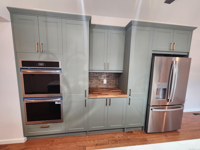 154 Falls Rd, East Haddam, CT 06469 - kitchen featuring appliances with stainless steel finishes, gray cabinets, light wood-style floors, butcher block countertops, and decorative backsplash