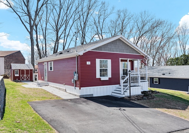 manufactured / mobile home with an outdoor structure, a front yard, and a storage unit