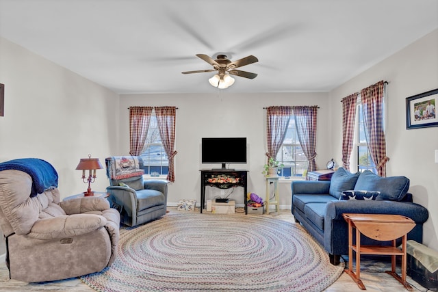 living room featuring baseboards, a healthy amount of sunlight, and ceiling fan