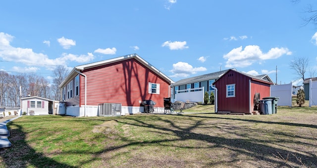 view of property exterior with an outdoor structure, a shed, cooling unit, and a lawn